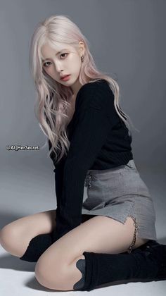 Woman with long pink hair wearing a black top and plaid skirt in a studio
