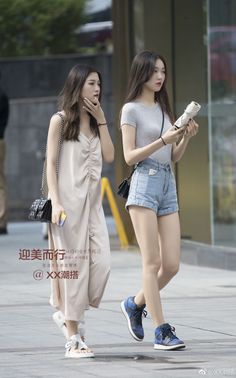 Two women walking on a street, one in a jumpsuit and the other in denim shorts