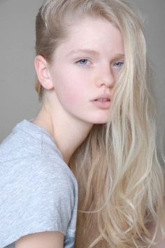 Young person with blonde hair and blue eyes wearing a grey t-shirt