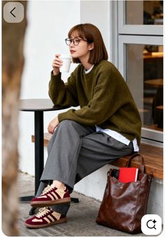 Woman with short hair and glasses sitting at an outdoor cafe with a coffee cup