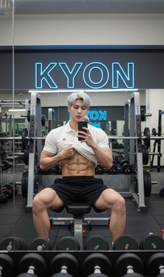 Muscular man with white hair taking a selfie in a gym, showing his abs