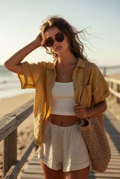 Woman in a yellow shirt and shorts on a beach boardwalk at golden hour