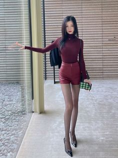 Woman in a burgundy turtleneck and red leather shorts posing indoors