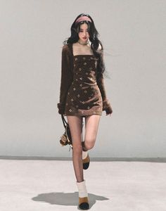 Woman in a brown dress and tights posing indoors