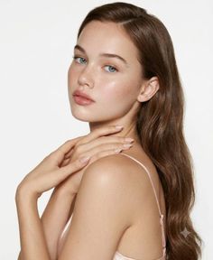 Woman with long brown hair and blue eyes wearing a pink top