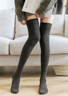 Person wearing a gray sweater and thigh-high socks indoors
