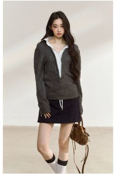 Woman with long dark hair wearing a knitted sweater, mini skirt, and knee-high socks