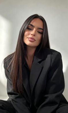 Woman with long dark hair wearing a black blazer, looking at the camera