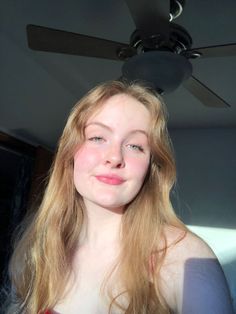 Young woman with long blonde hair and blue eyes indoors with soft lighting