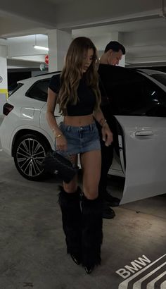 Woman in a crop top, denim skirt, and fur boots in a parking garage