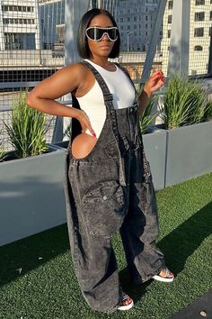 Woman in denim overalls with cutouts and sunglasses posing outdoors