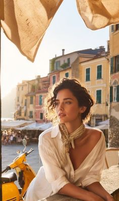 Woman with curly hair and a white shirt in a sunlit European cityscape