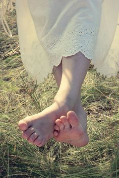 Bare feet on grass with a white embroidered dress