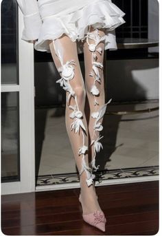 Person in a white dress with sheer floral stockings and pink shoes