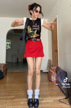 Woman in a red skirt and black top posing indoors