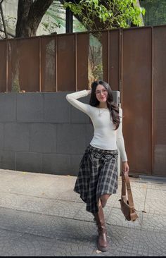 Woman with long hair wearing a plaid skirt and knee-high boots on a street
