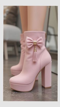 Pair of pink high-heeled platform ankle boots with a bow and tassel detail
