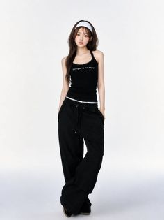 Woman in a black tank top and baggy pants with a white headband
