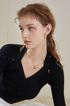 Woman with long hair wearing a black top and gold jewelry