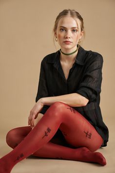 Woman with blonde hair and freckles wearing red tights and a black shirt