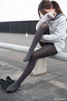 Woman in a school uniform and black tights sitting outdoors