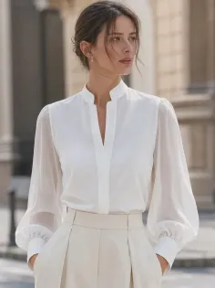 Woman in a white blouse with sheer sleeves and light pants outdoors