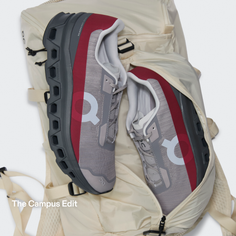 Pair of grey and red running shoes on a light-colored backpack