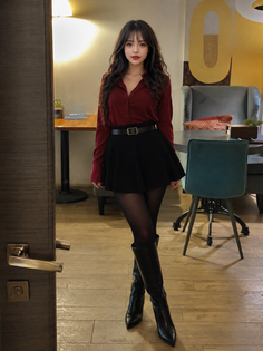 Woman in a red shirt and black skirt with long dark hair standing indoors
