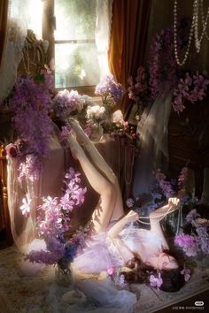 Woman with long hair surrounded by purple flowers and pearls, lying on the floor