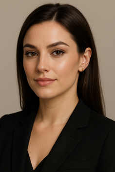 Woman with dark hair wearing a black blazer and gold earrings