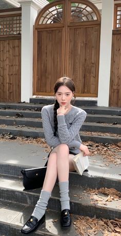 Woman with a long braid sitting on outdoor steps with autumn leaves