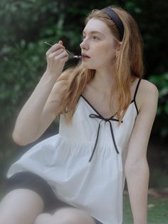 Woman with red hair and a white top eating outdoors