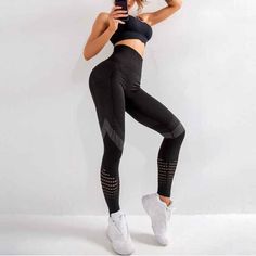 Woman in black sports bra and leggings with white sneakers posing indoors
