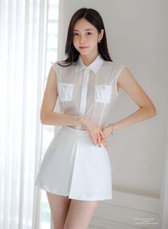 Woman in a white sheer top and mini skirt posing indoors