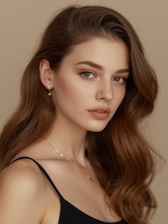 Woman with long wavy hair and green eyes wearing a black top and gold jewelry