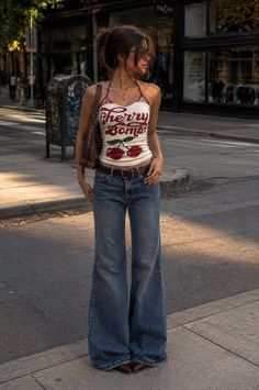 Woman in a halter top and flared jeans standing on a city street