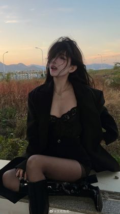 Woman with long black hair wearing a black jacket and corset at sunset