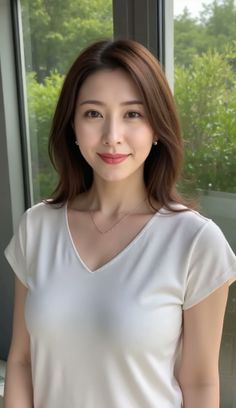 Woman with brown hair wearing a white t-shirt and jewelry indoors