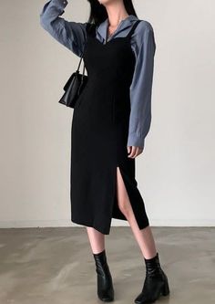 Woman in a black slip dress over a blue shirt with black ankle boots and handbag