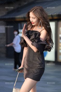 Woman in a black dress with long hair and red lipstick outdoors
