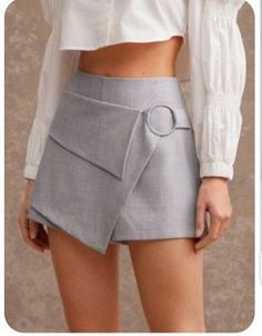 Woman wearing a gray skort and white crop top, showing her midriff