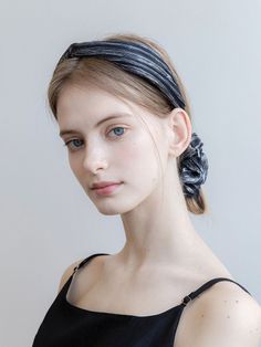 Woman with blonde hair and blue eyes wearing a black top and headband