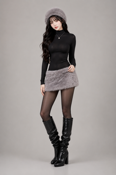 Woman in a black top, fur skirt, and black boots posing in a studio