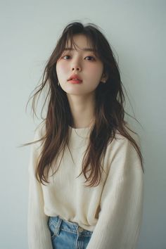 Woman with long brown hair wearing a light sweater and blue jeans