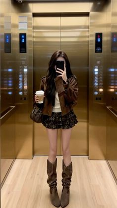 Woman in a brown jacket and leopard print skirt taking a selfie in an elevator
