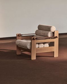 A modern wooden chair with cylindrical cushions on a brown floor