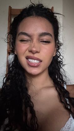 Woman with curly hair winking and smiling with glossy lips