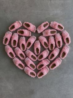 Pink fur slippers with silver claws arranged in a heart shape on a concrete floor