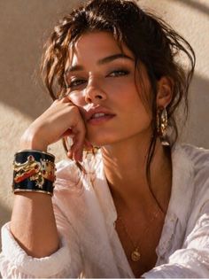 Woman with a messy bun and gold jewelry in soft, warm lighting