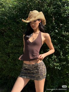 Woman in a straw hat, halter top, and leopard print mini skirt outdoors